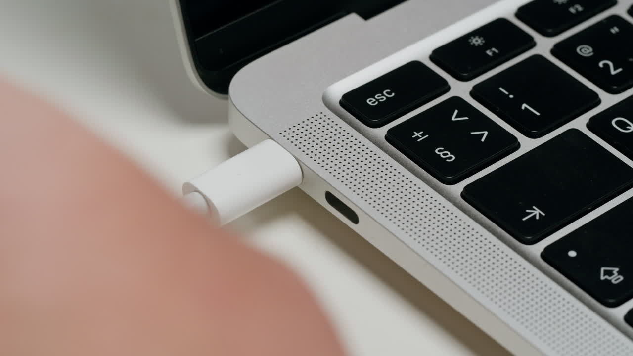 Hand plugging a USB-C cable into a laptop