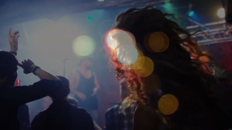 Happy-diverse-people-dancing-and-raising-hands-during-concert-over-light-spots