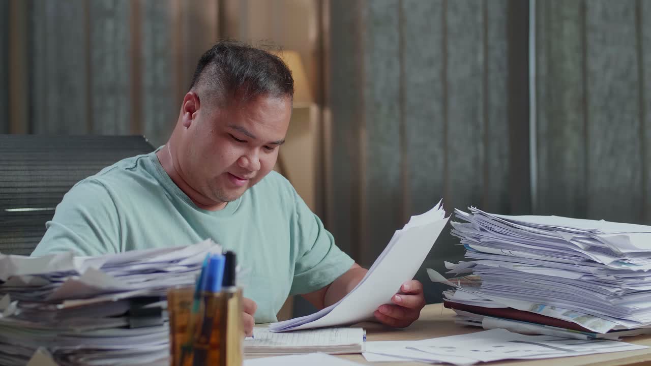 Close Up Of Smiling Fat Asian Man Enjoys Working With Documents At The Office
