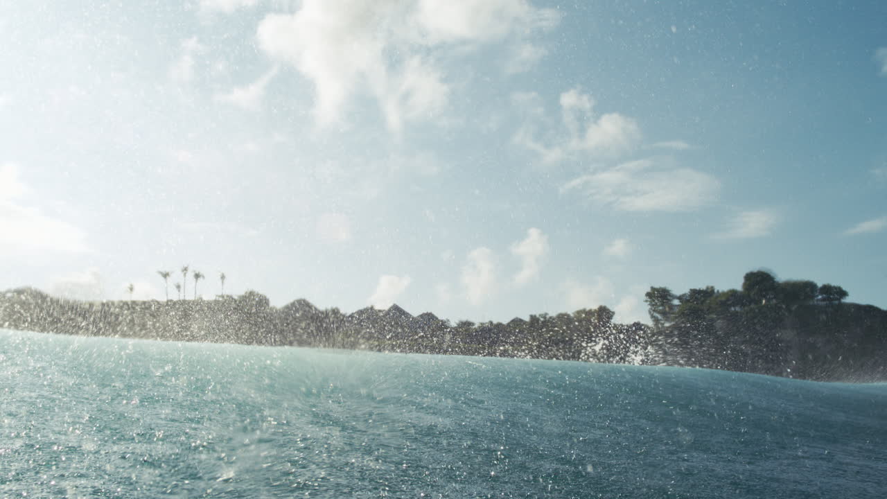 Tropical ocean with sunlit surface sparkles, island coastline in distance