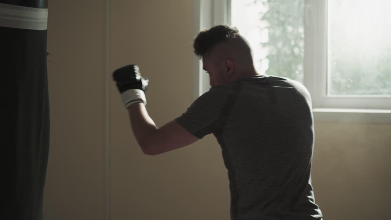 Man adjusts punching bag before hitting in sports club. Sportsman exercises with heavy inventory in fighting gym slow motion. Combat training