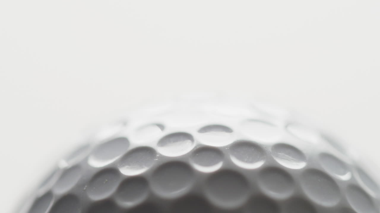 Close-up van golfbal op witte achtergrond, kopieerruimte, slow motion