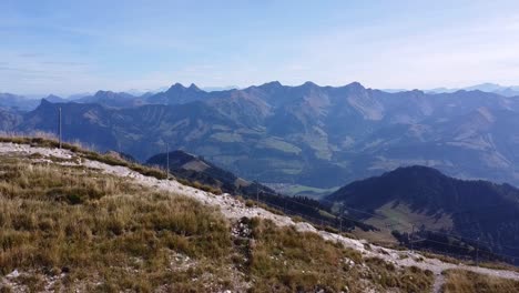 Der-Drohnenflug-Verläuft-Von-Links-Nach-Rechts-Und-Zeigt-Einen-Kleinen-Pfad-Auf-Der-Spitze-Eines-Hügels.-Der-Hintergrund-Ist-Mit-Bergen-Gefüllt