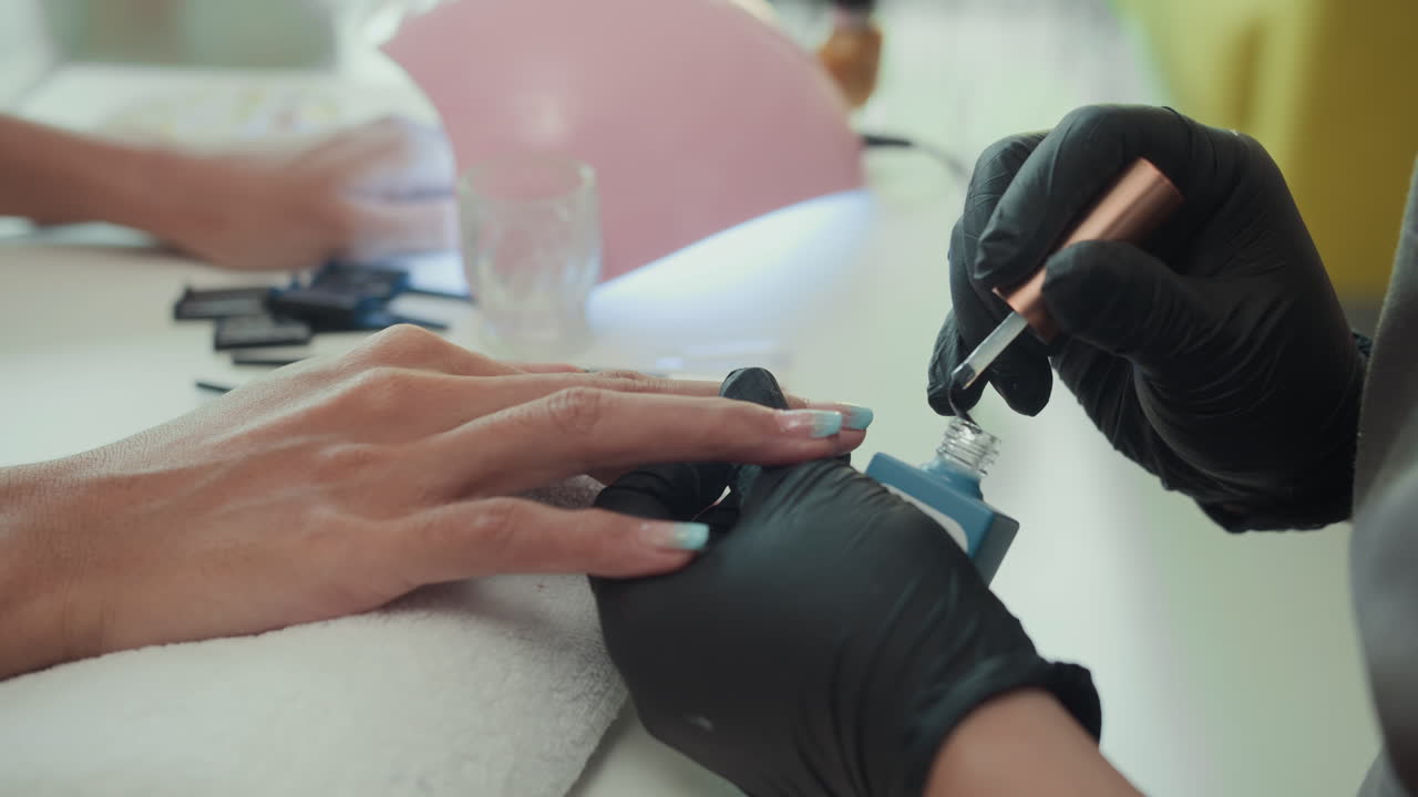 Spécialiste appliquant du vernis gel transparent sur les ongles d’une cliente