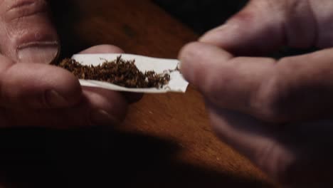 a man's hands rolling a cigarette and adding a filter, close up