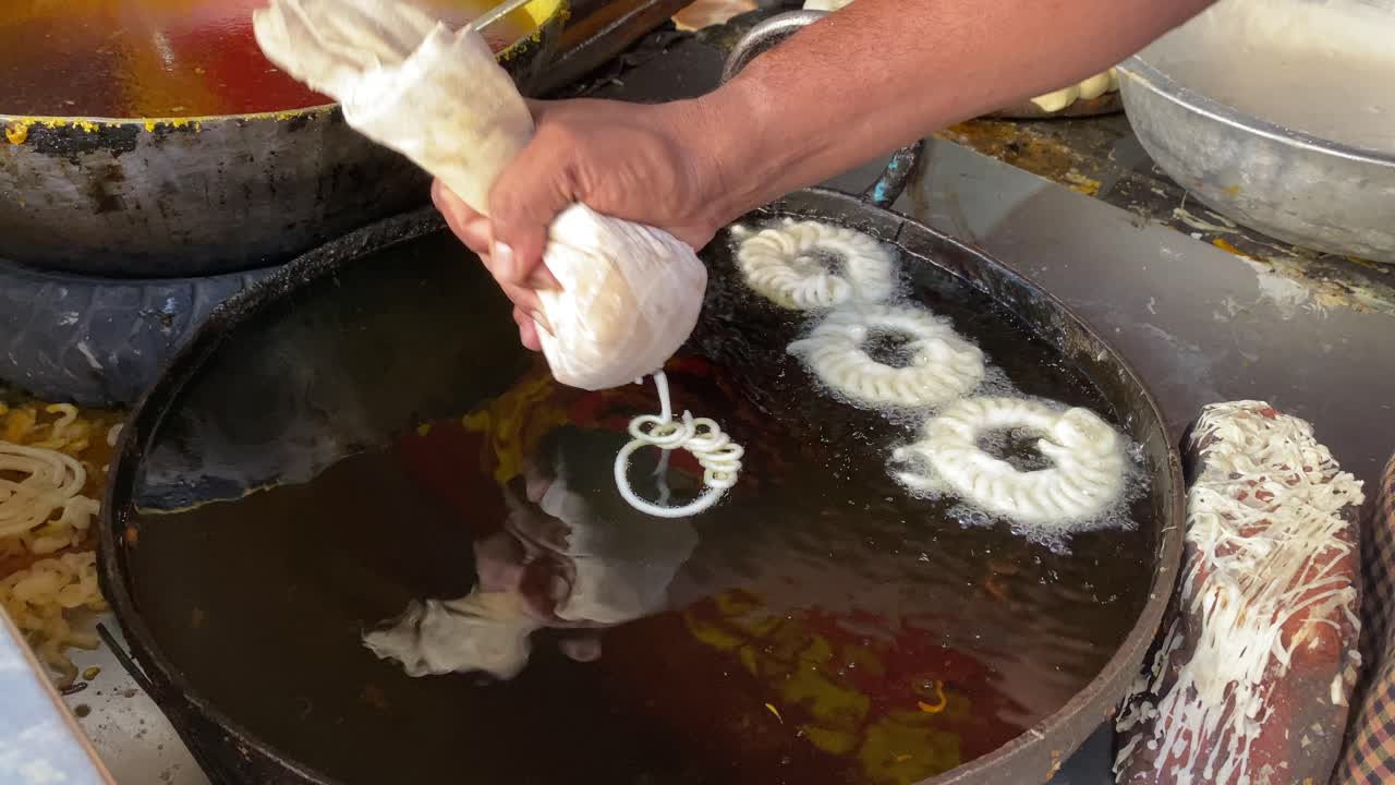 hombre haciendo bocadillos tradicionales de jalebi de naranja dulce en un mercado de comida callejera en bocadillos sharma en kolkata, india