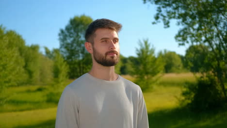 portrait of a man standing in a sunny green park