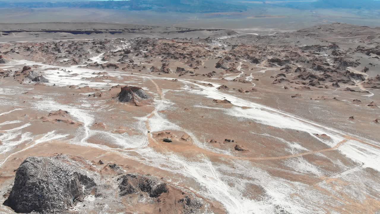 tiro aéreo de drones acercándose a un autobús abandonado con dos viajeros en el techo en el desierto de atacama, sudamérica, chile