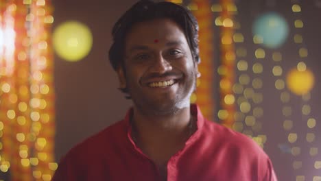 Portrait-Of-Smiling-Asian-Man-Celebrating-Diwali-Against-Bokeh-Lighting-Background