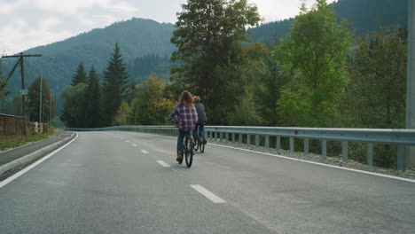 Couple-riders-cycling-mountains-together-on-highway-road.-Travelers-enjoy-bikes.