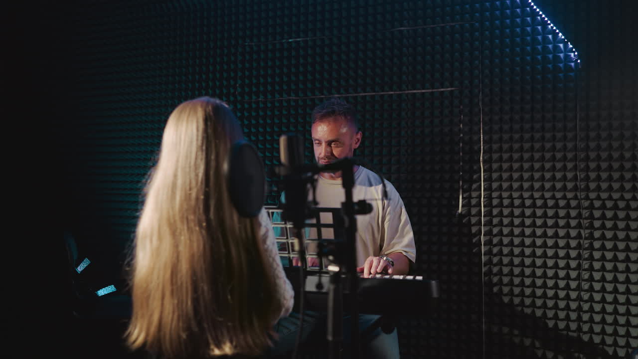 el mentor practica la canción con el niño en el estudio. el maestro toca el piano y observa a la niña mentee cantando en el espacio de grabación de audio. entrenamiento vocal