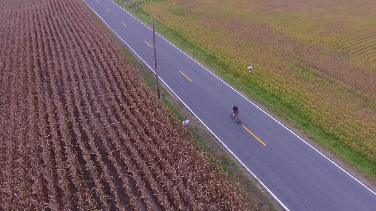 Aerial view of young man riding his bike down the road in the country in 4K