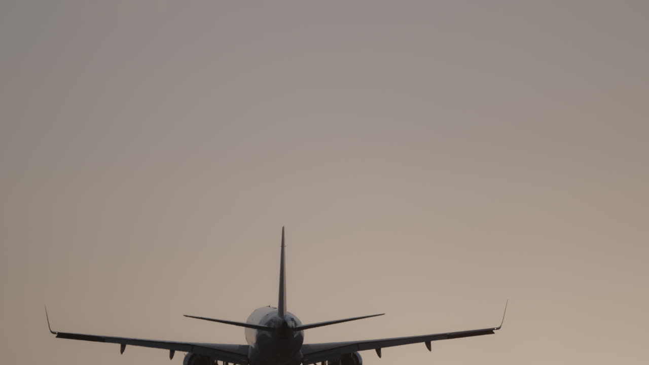 Avión volando en el cielo para aterrizar en el aeropuerto a cámara superlenta al atardecer