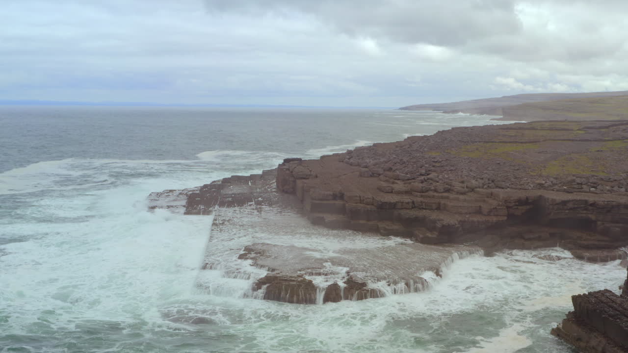 Aerial descending tilt reveals Doolin's dramatic rocky coastline and layered stone formations