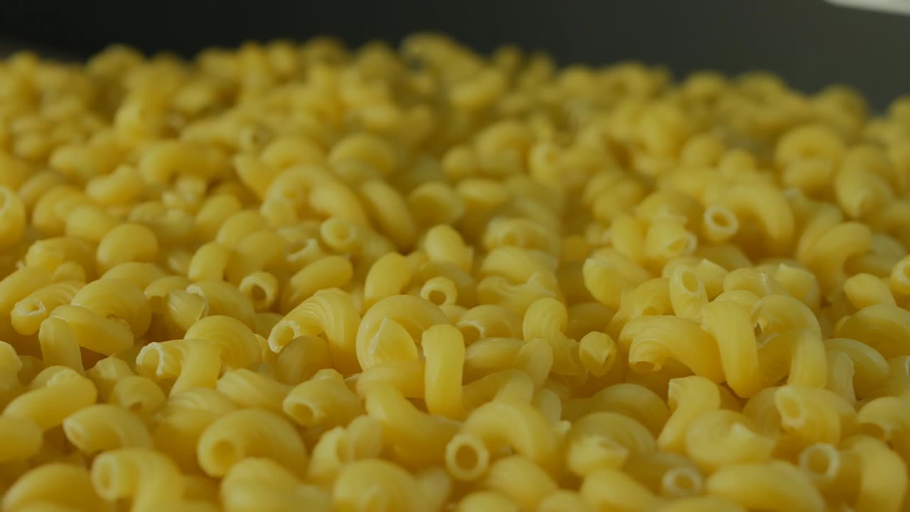 girar una gran pila de pasta sin cocer, encendido en la oscuridad. primer plano