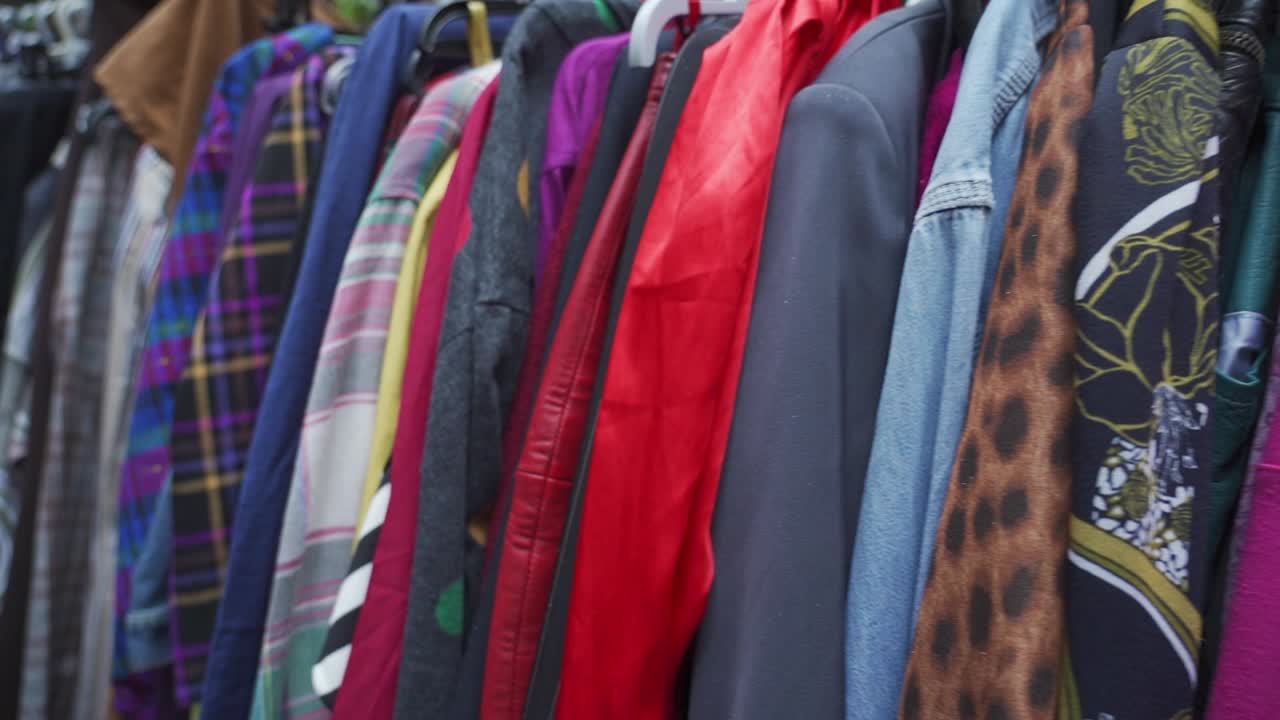 A clothing rack full of colorful items at a second-hand market