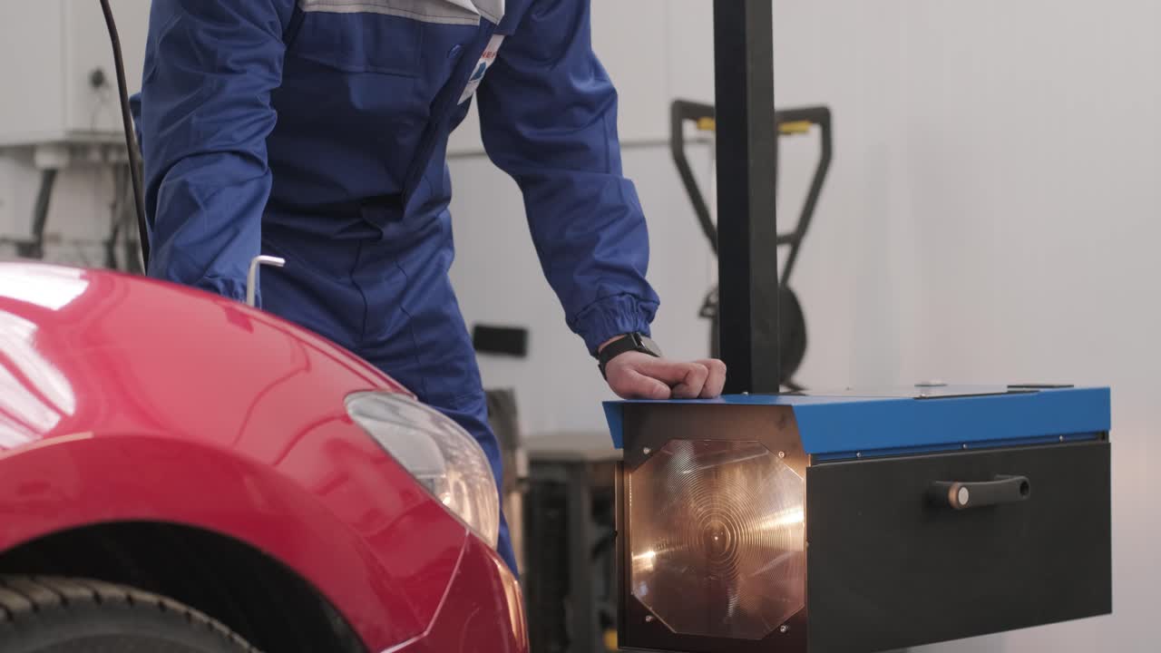 trabajador comprueba y ajusta los faros del sistema de iluminación de un automóvil. servicio de reparación de automóviles.