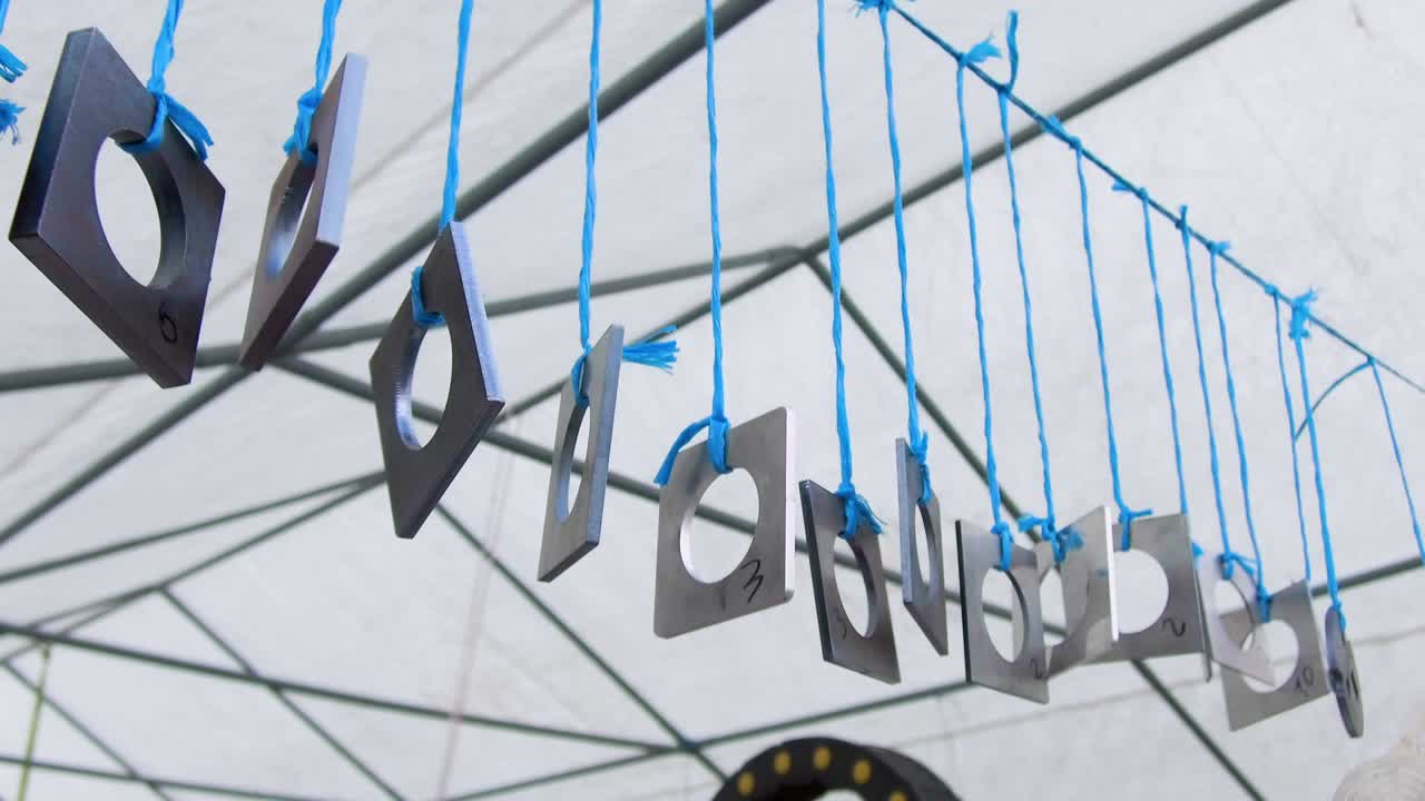 구이 있는 금속 사각형 판. 금속 제품은 파란색 로프에 매달려서 불어오는 바람에서 흔들립니다.