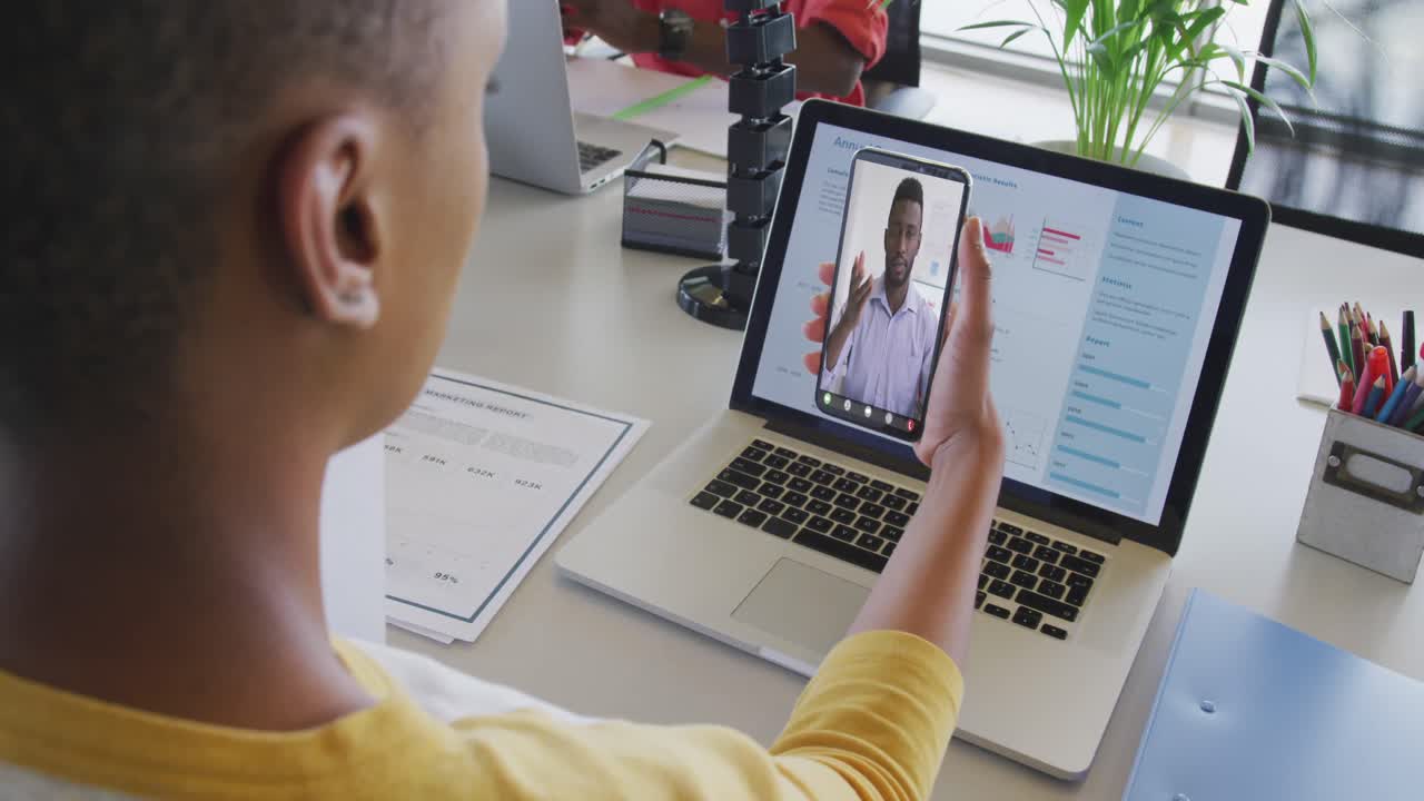 Video of biracial woman having video call on smartphone with african american male coworker
