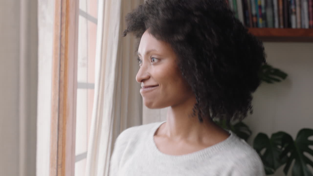 beautiful african american woman opening curtains looking out window stretching enjoying fresh new day feeling rested