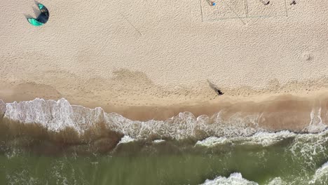 AERIAL:-Top-Shot-of-Couple-Walking-on-Sandy-Beach-Holding-Hand-near-Baltic-Sea