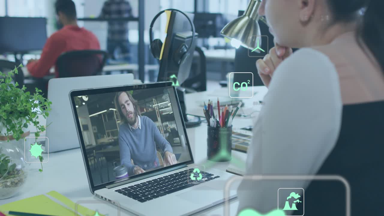 Woman watching laptop as man onscreen gesturing, AR overlays popping around desk showing CO2 charts