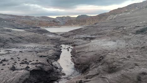 una pequeña corriente de agua fluye hacia un depósito de agua casi vacío para la central hidroeléctrica - lago grondalsvatnet en eksingedalen noruega - bajo nivel de agua - tiro estático desde el interior de la presa propiedad de bkk