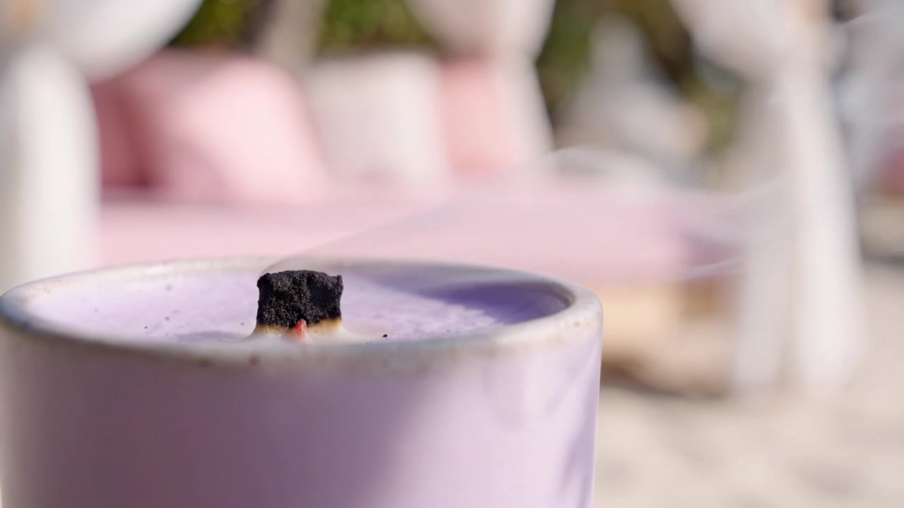 Une bougie paisible allumée sur un transat de plage relaxant, entourée de tissus doux et d'une ambiance naturelle, évoquant la sérénité et la tranquillité dans un cadre magnifique