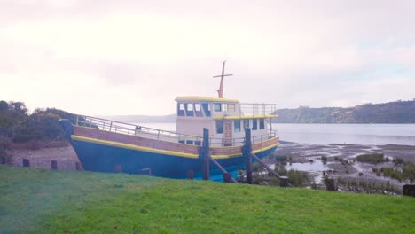 Barco-Solitario-Y-Humo-De-Curanto-En-La-Costa-De-Castro,-Chiloé,-Sur-De-Chile.