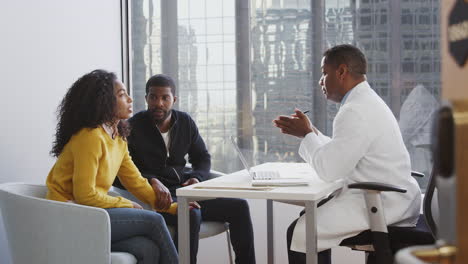 Una-Pareja-Preocupada-Consultando-Con-Un-Médico-Varón-En-El-Consultorio-Del-Hospital