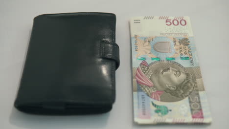 panning footage from right to left: 500 polish zloty with black wallet on table, no popular money in country