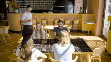 group of friends sitting at a restaurant table while they talk to each other