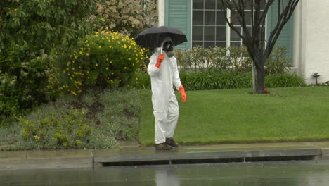 Ein-Mann-In-Einem-Schutzanzug-Hält-Einen-Regenschirm-Und-überquert-Die-Straße