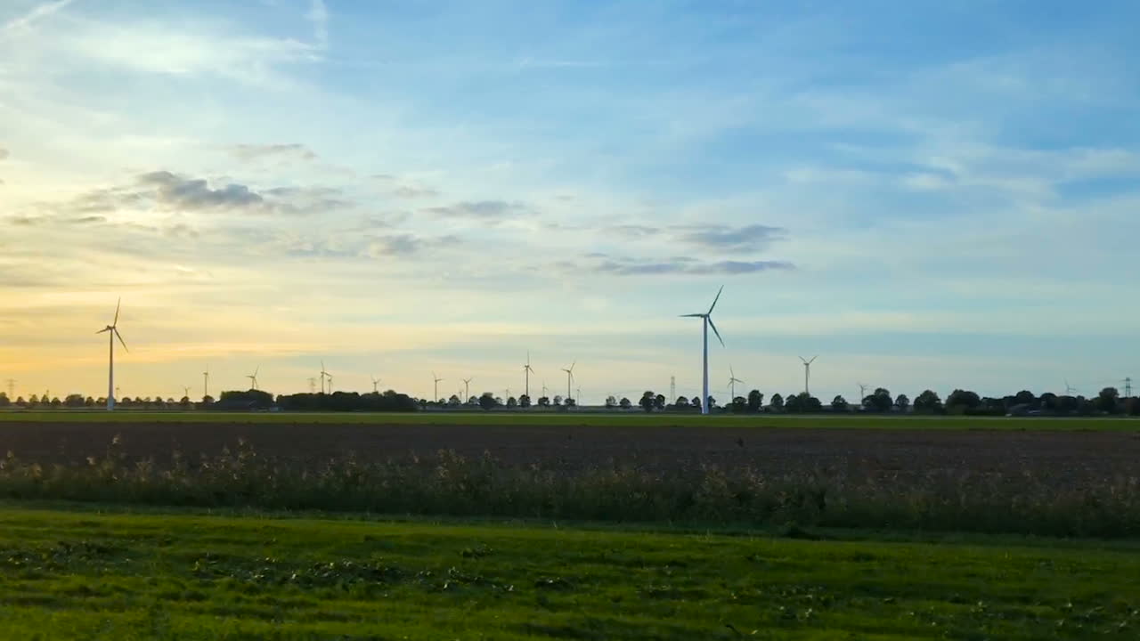 석양에 회전하는 풍력 터빈을 따라 도로
