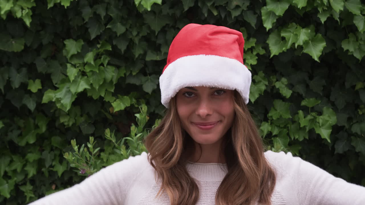 At Christmas, Smiling woman wearing Santa hat outdoors, enjoying festive holiday season