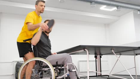 a young man with limited physical abilities is practicing to play table tennis a young man with limited physical abilities is practicing to play table tennis rehabilitation of the athlete with the help of a coach