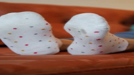 close up of a pair of worn white polka dot socks on a couch