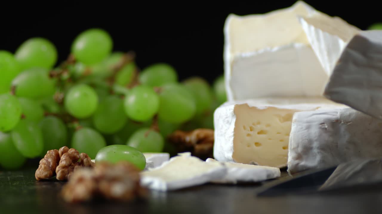 Pieces of Camembert cheese with grapes slowly rotating.