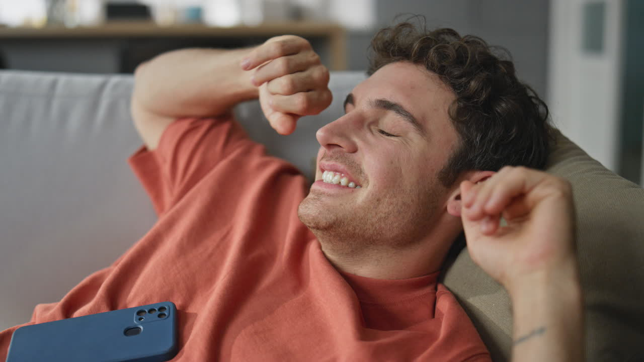 Relaxed man messaging smartphone laying sofa closeup. Carefree guy chilling