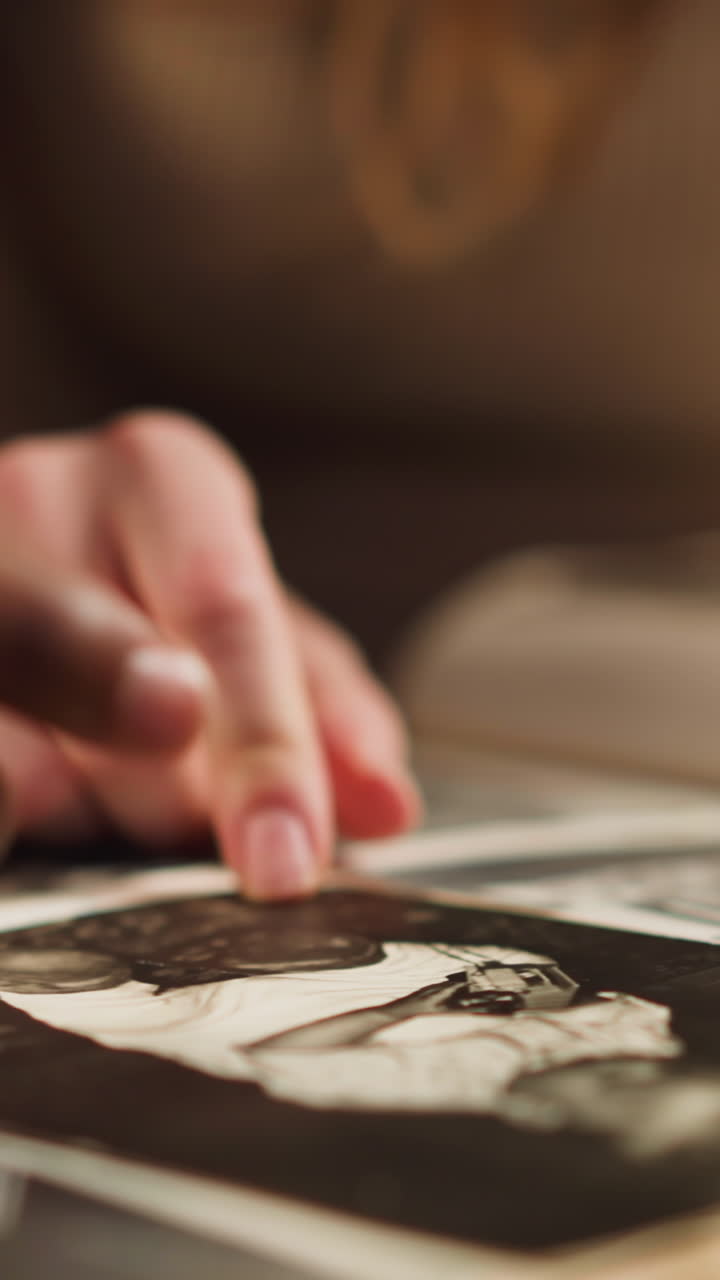 White lady with African-American boyfriend points to baby picture of grandmother looking through old photo-album in living room closeup slow motion