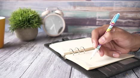 persona escribiendo en un cuaderno en un escritorio