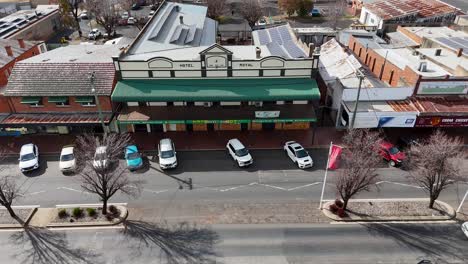 drone footage captures parked cars, moving vehicles, and commercial buildings on a sunny day in coonabarabran, new south wales, with steady overhead movement