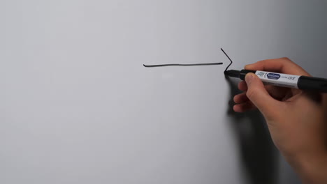 hand drawing an arrow on a whiteboard with a black marker