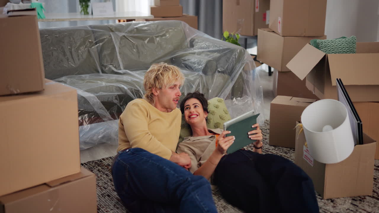 Young Couple Planning New Home Layout with Tablet Amidst Moving Boxes