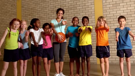 Cute-pupils-showing-thumbs-up-with-pe-teacher