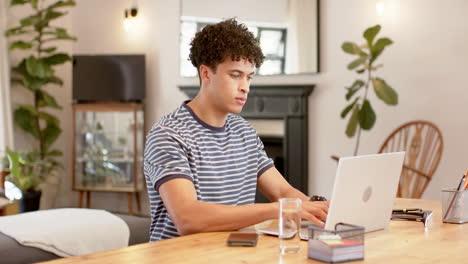 biracial man working from home using laptop, slow motion