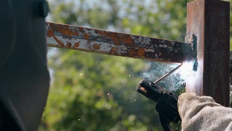 close craftsman welds upper rail of metal fence on sunny day