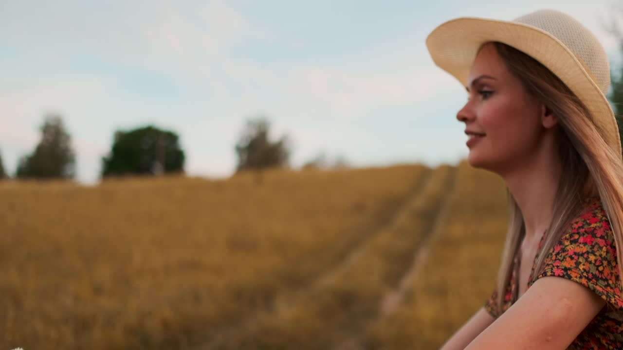 feliz y alegre niña con un sombrero monta una bicicleta en un vestido con flores en el campo y sonríe disfrutando del verano y la libertad