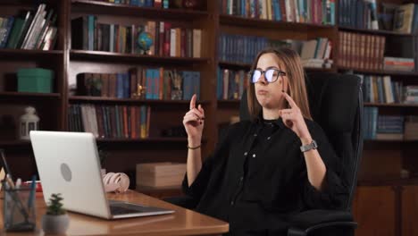 the girl is sitting and talking to someone via a video call using a laptop