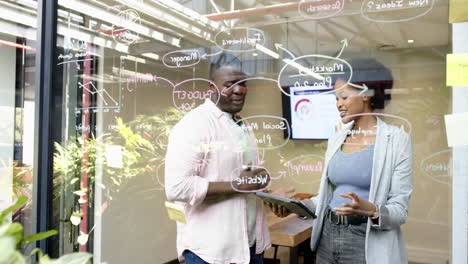 african american colleagues discussing ideas while writing on glass board